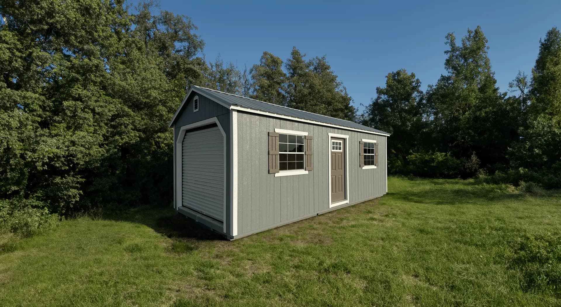 Stor-Mor 12x24 portable garage in gray with a white roll-up overhead door, a side personnel door and two shuttered windows